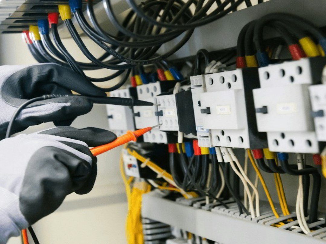 Electrician testing wiring in a control panel